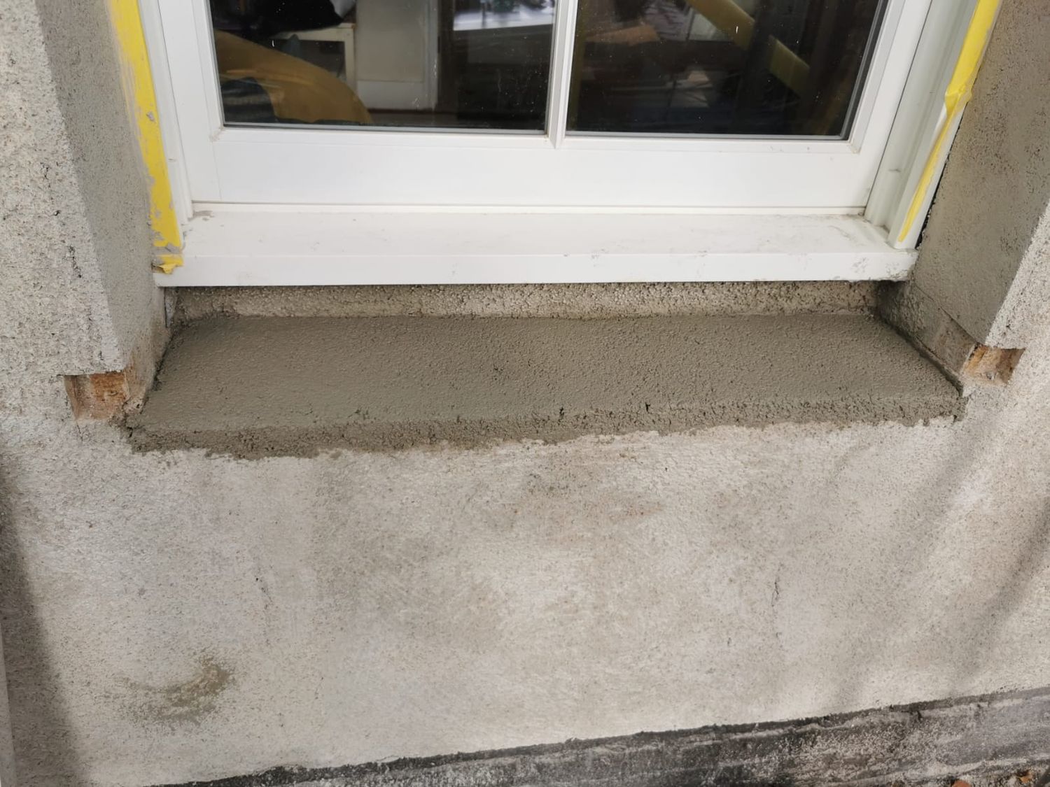 Insulating render applied around external window reveals to reduce thermal bridge
