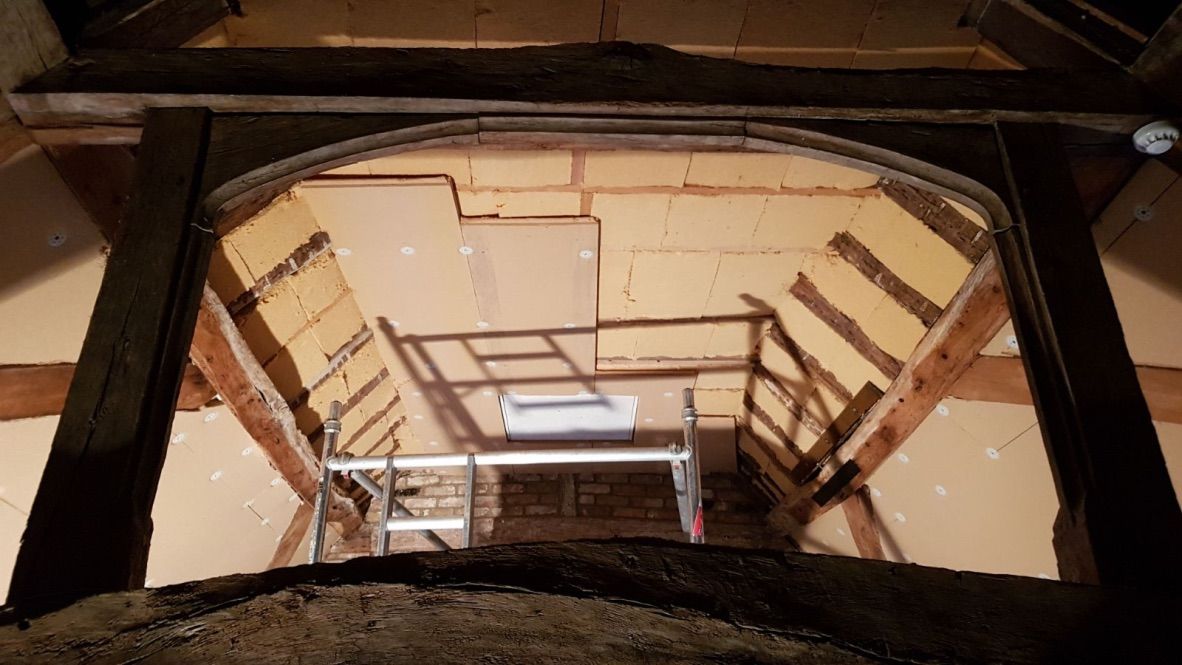 Flexible wood fibre insulation batts installed between rafters, wood fibre boards are being fitted under rafters