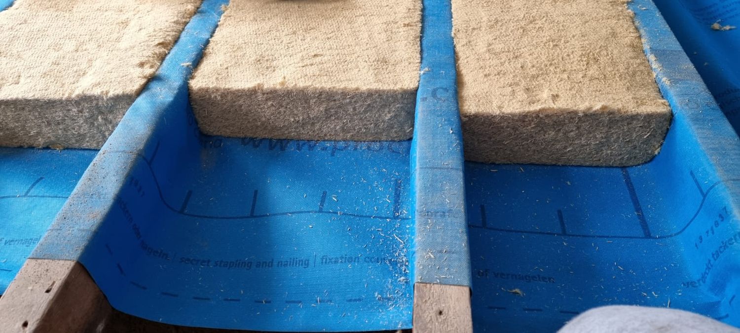 Suspended floor insulation - Gutex flexible wood fibre insulation being installed between floor joists