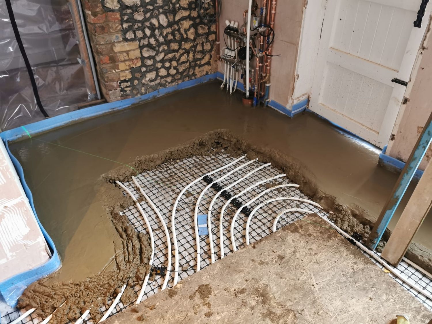 New solid floor being installed with embedded wet underfloor heating pipes & perimeter insulation