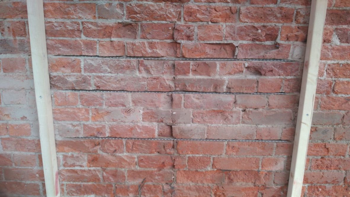 Brick wall structurally strengthened with helical bar stitching before insulation applied